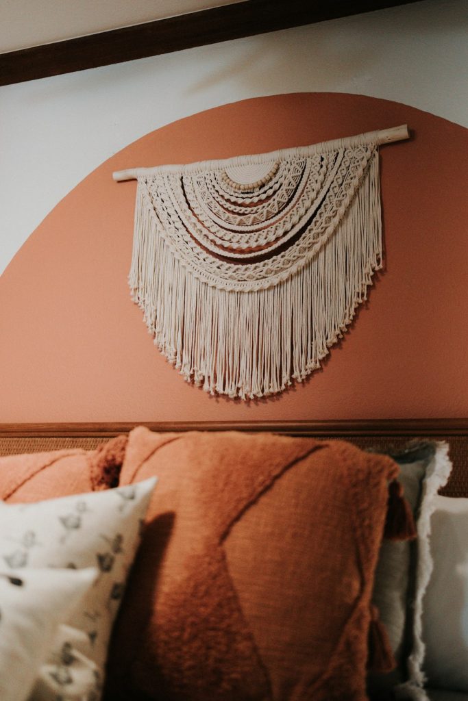 a-close-up-of-a-bed-with-pillows-and-a-wall-hanging-eseuahxu8yk